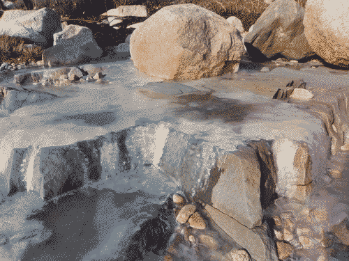 Ice flows over the rocks on the beach in Steuben, ME