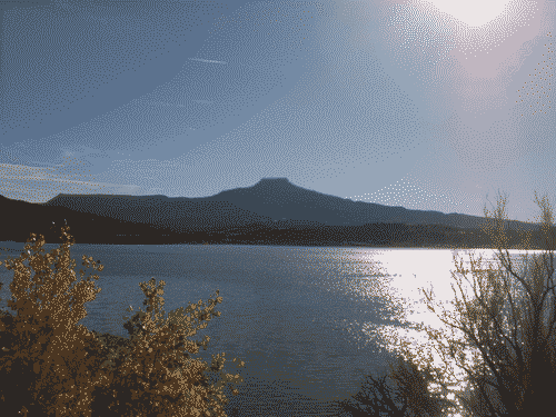 View across the lake to a glorious mesa lit from behind, and the sun shining on the water at Abiquiu Lake