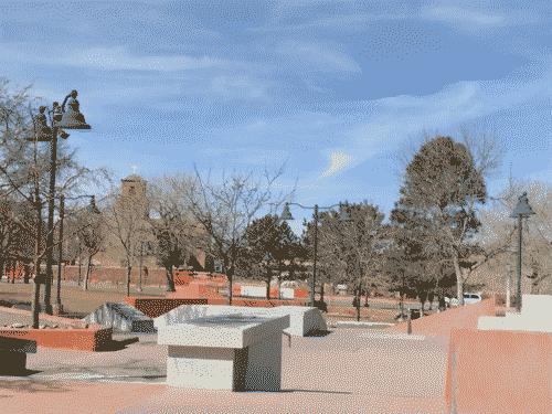 View across De Vargas Skatepark and the green space adjacent, with the cathedral visible across the street amist the barren trees