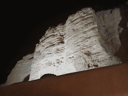 Off-white rock face frontlight in the pitch black night
