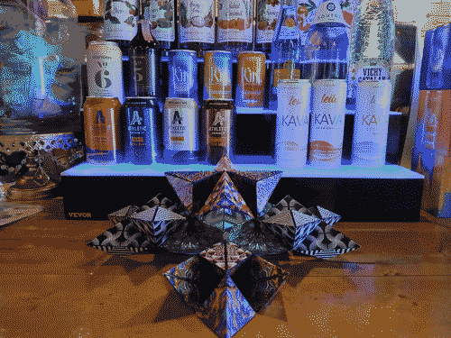 Colorful puzzle cubes unfolded/arranged and stacked on the counter in front of a large array of non-alcoholic drinks, with ambient blue lighting