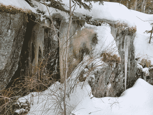 Refrozen snowmelt covers a mossy verdigris rock
